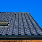 A vertical low angle closeup shot of the black roof of a building with a blue background